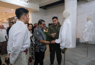 Menteri Ekonomi Kreatif/Kepala Badan Ekonomi Kreatif (Ekraf), Teuku Riefky Harsya (tengah), mendengarkan penjelasan mengenai busana dari perancang busana Ivan Gunawan (kanan) saat menghadiri pameran instalasi mode bertajuk “Gaya Archive Chapter 4” di Senayan City, Jakarta, Kamis (24/09/2026).